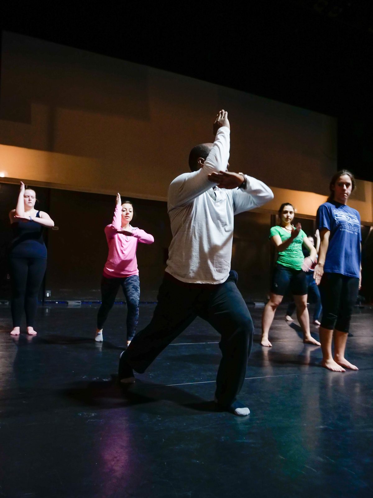 Boris Willis in a deep lunge with crossed arms, dancers echoing the shape behind him