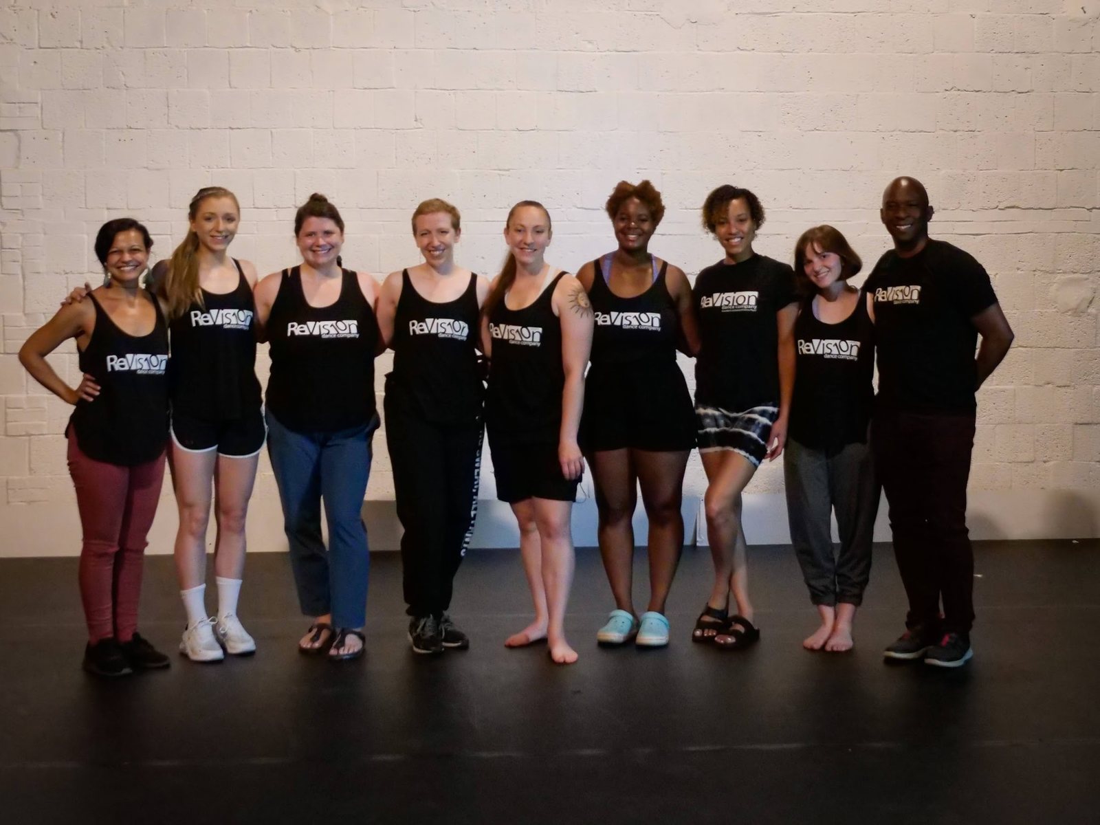 The ReVision Dance Company posed together against a white brick wall